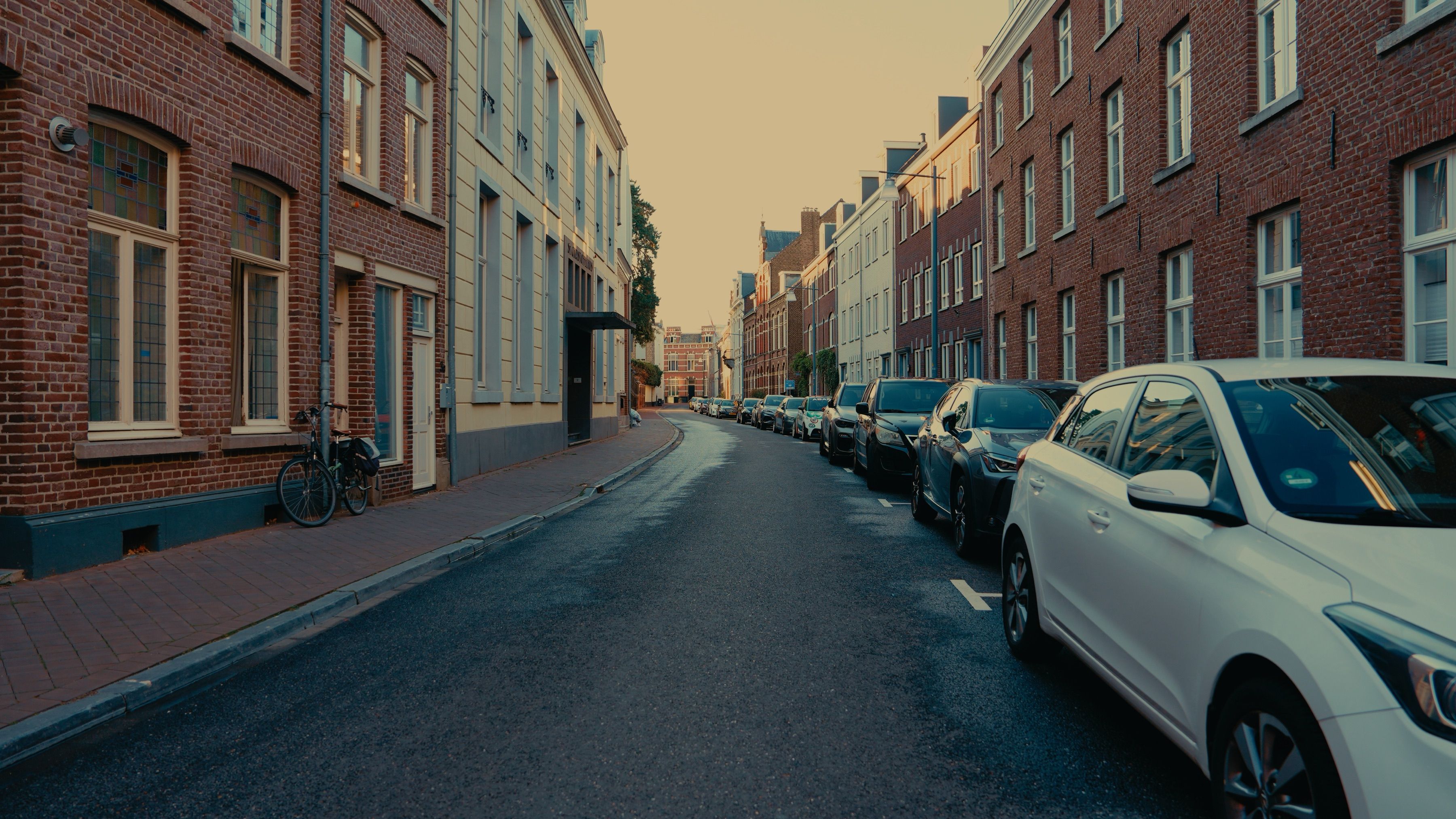 Rustige woonstraat in avondlicht met geparkeerde auto's langs beide zijden